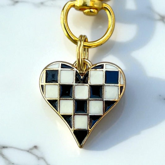Heart-shaped keychain with checkered pattern on a marble surface