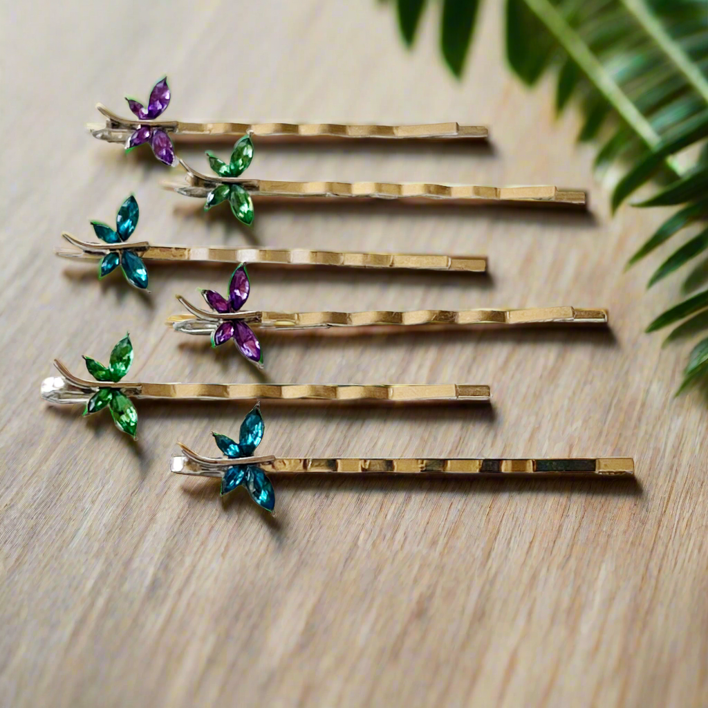 Purple, green, and teal dragonfly hair pins in a rainbow fan display