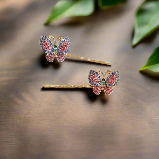 Set of two multicolor rhinestone butterfly hair pins on wood background