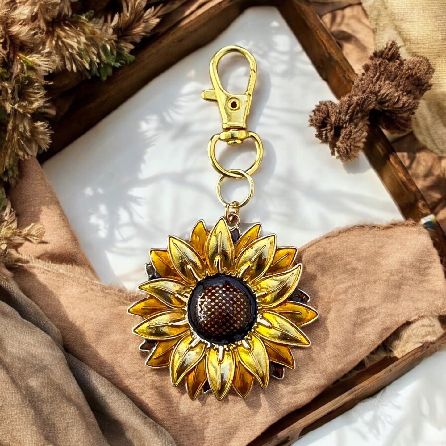 Sunflower handbag charm displayed with rustic textures and linens