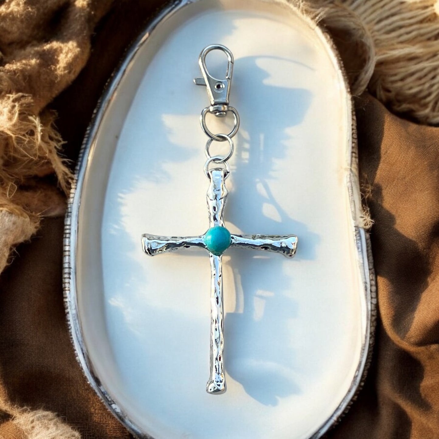 Close-up of boho turquoise cross bag charm with detailed design