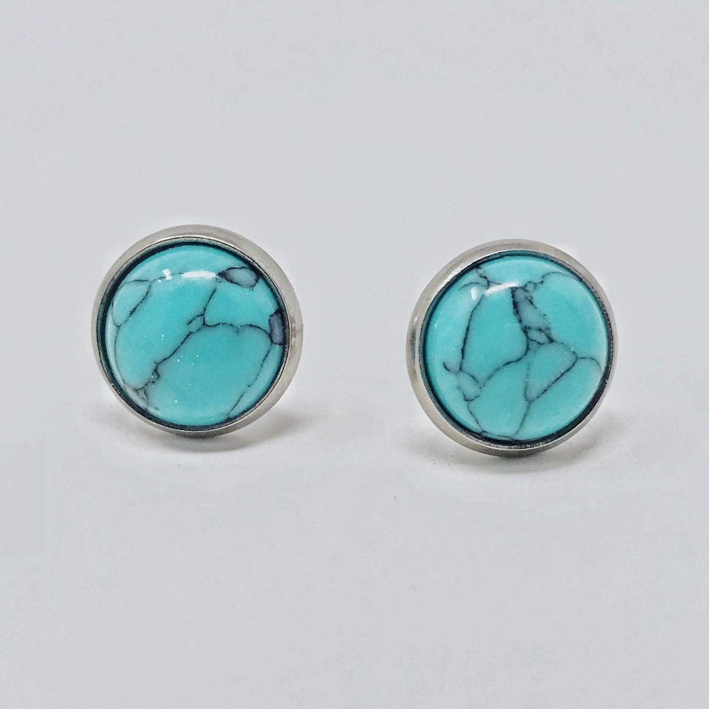 Round turquoise stud earrings in a silver-tone setting displayed on a white background