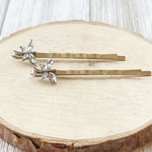 Clear rhinestone dragonfly hair pins on round wood slice background