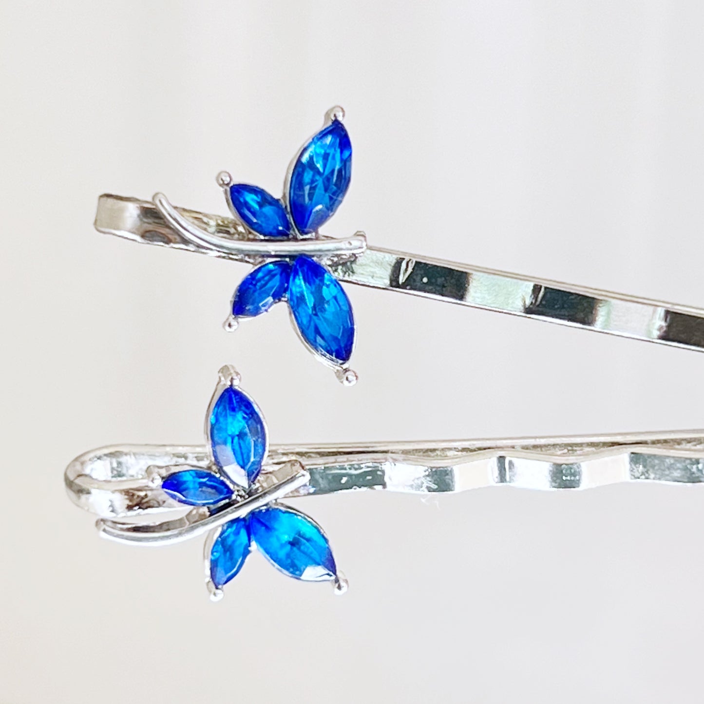 Close-up of tiny blue rhinestone dragonfly embellishments on silver bobby pins