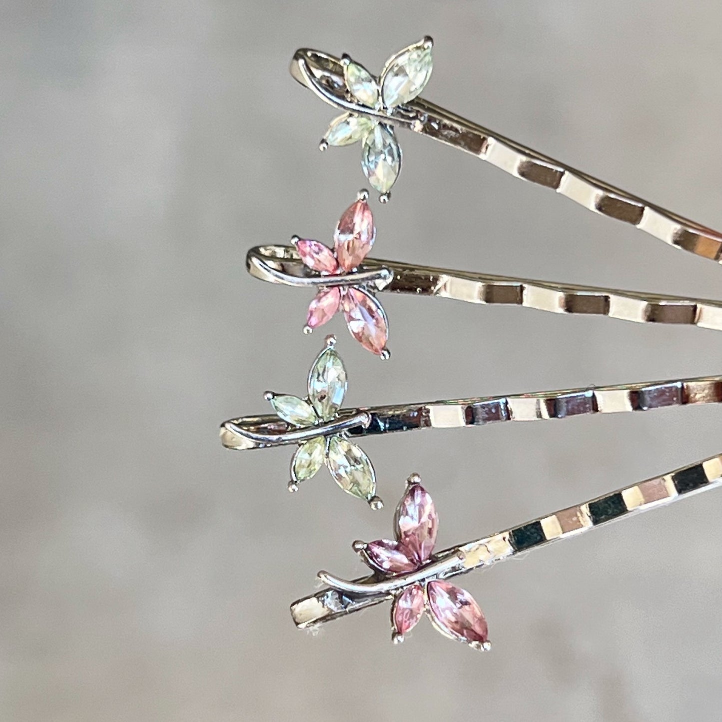 Close-up of handmade pink and green rhinestone dragonfly hair pins