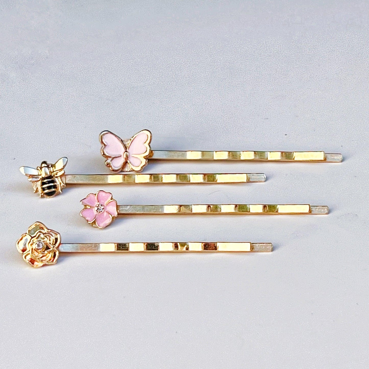Whimsical hair pin set with gold and pink floral and insect embellishments