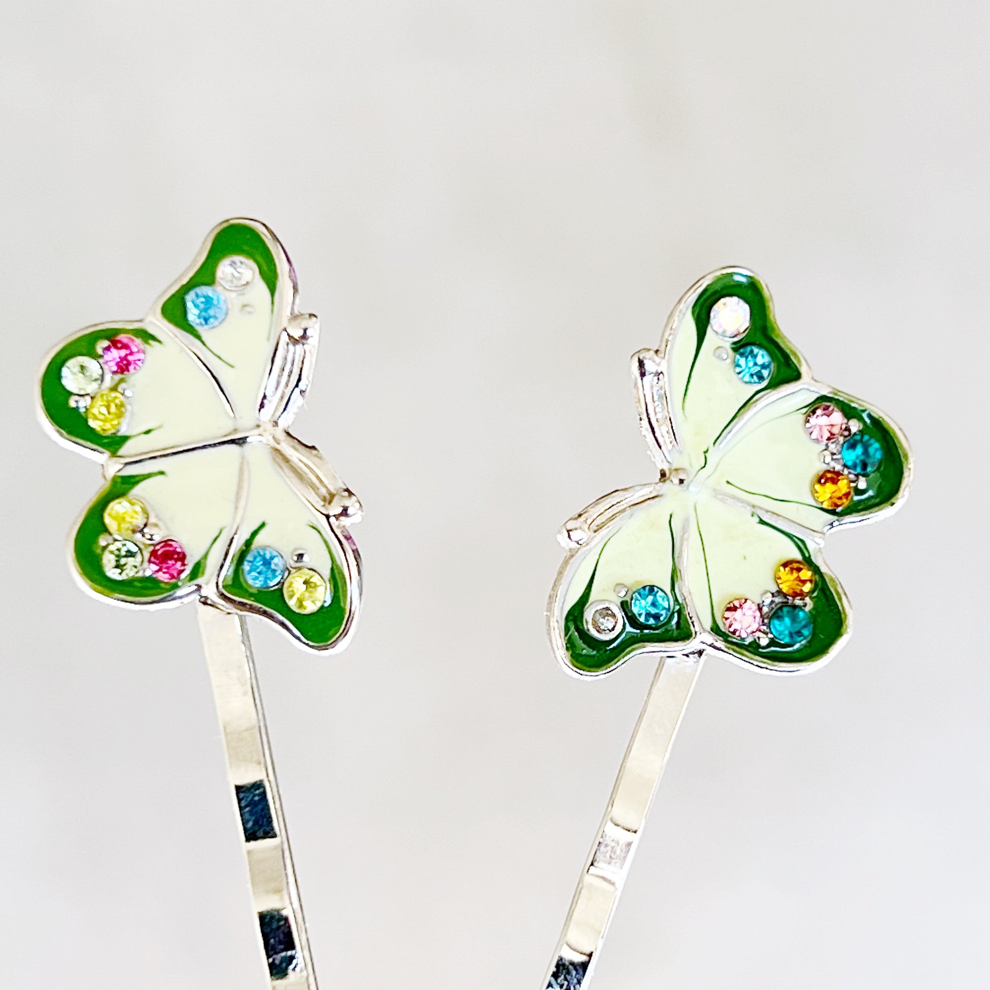 Close-up of green enamel butterfly hair pins with multi-colored rhinestones