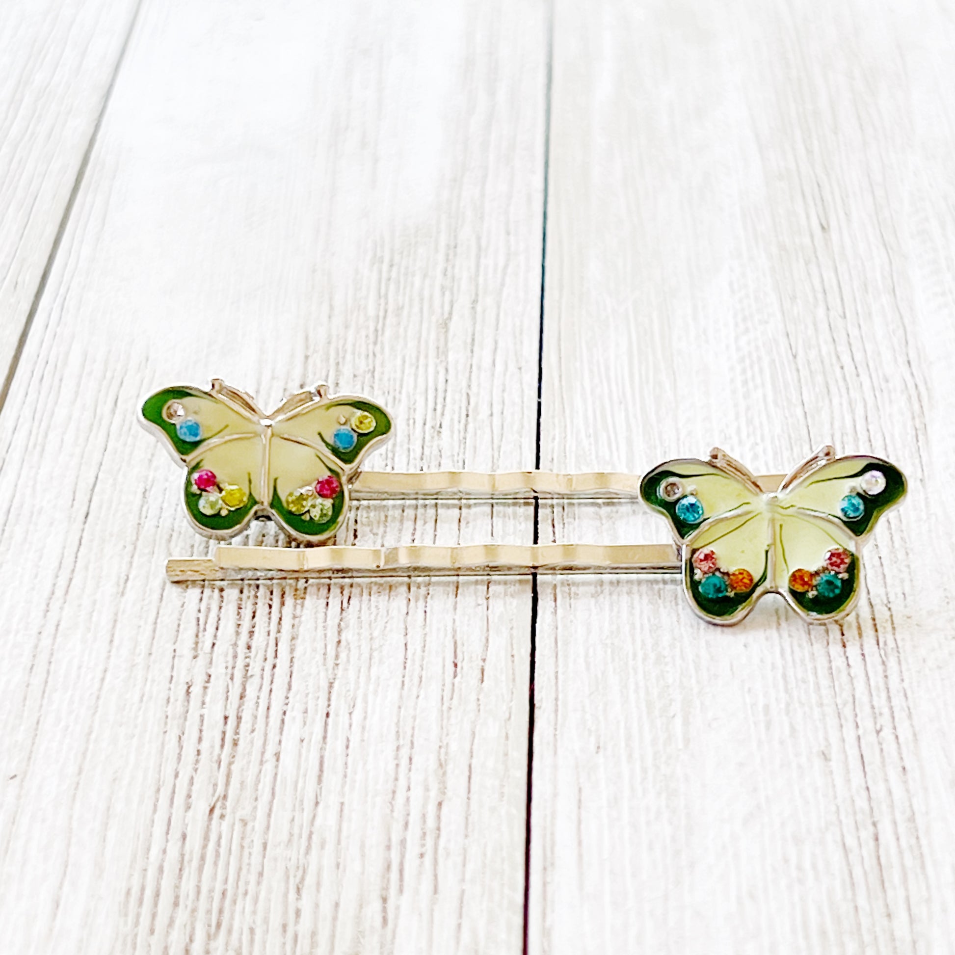 Pair of green butterfly hair pins on marble background