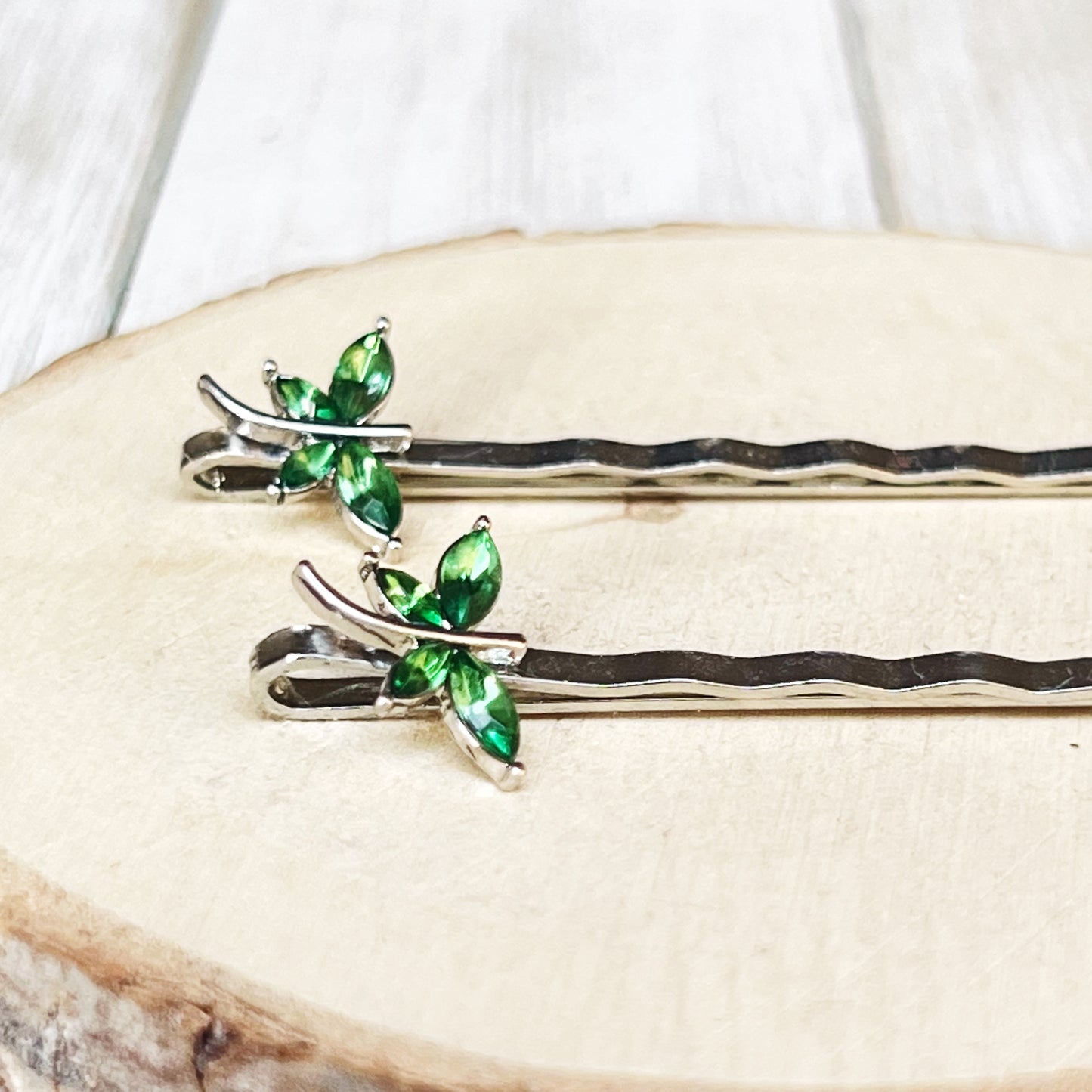 Close-up of green rhinestone dragonfly bobby pins with silver tone finish