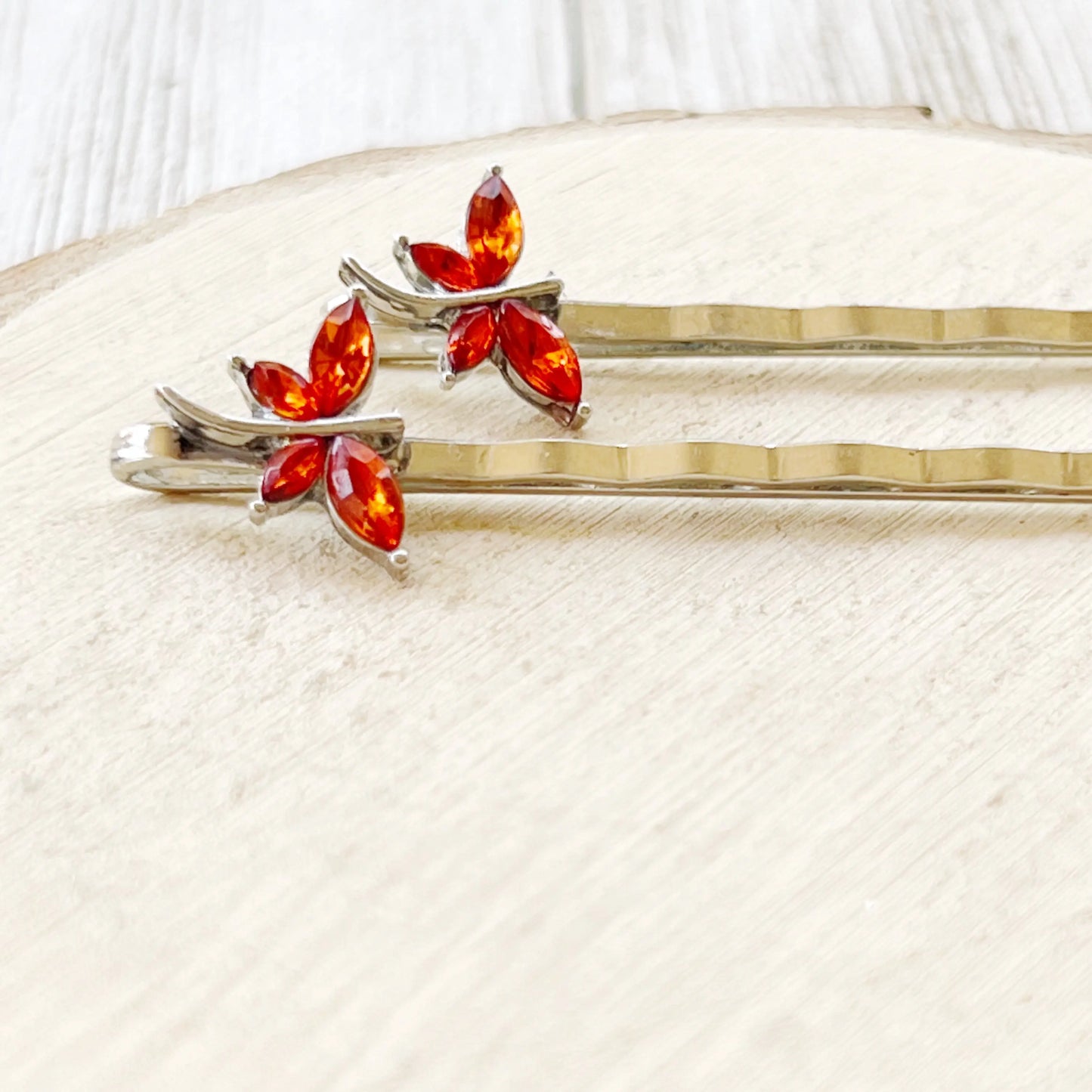 Orange dragonfly hair pins measured on scale grid