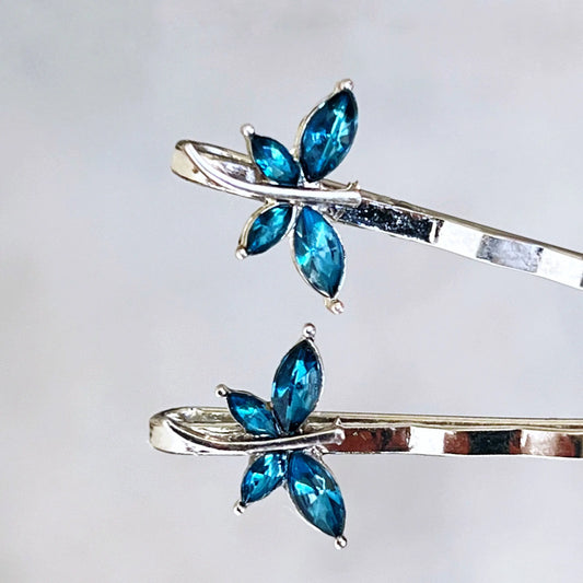 Close-up of teal rhinestone dragonfly bobby pins with silver setting