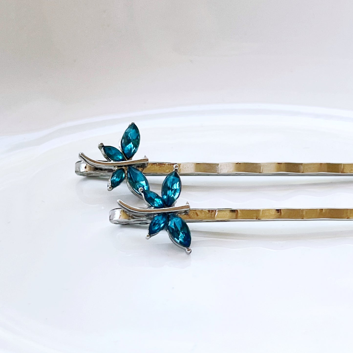 Teal dragonfly hair pins on white plate background – whimsical spring accessory