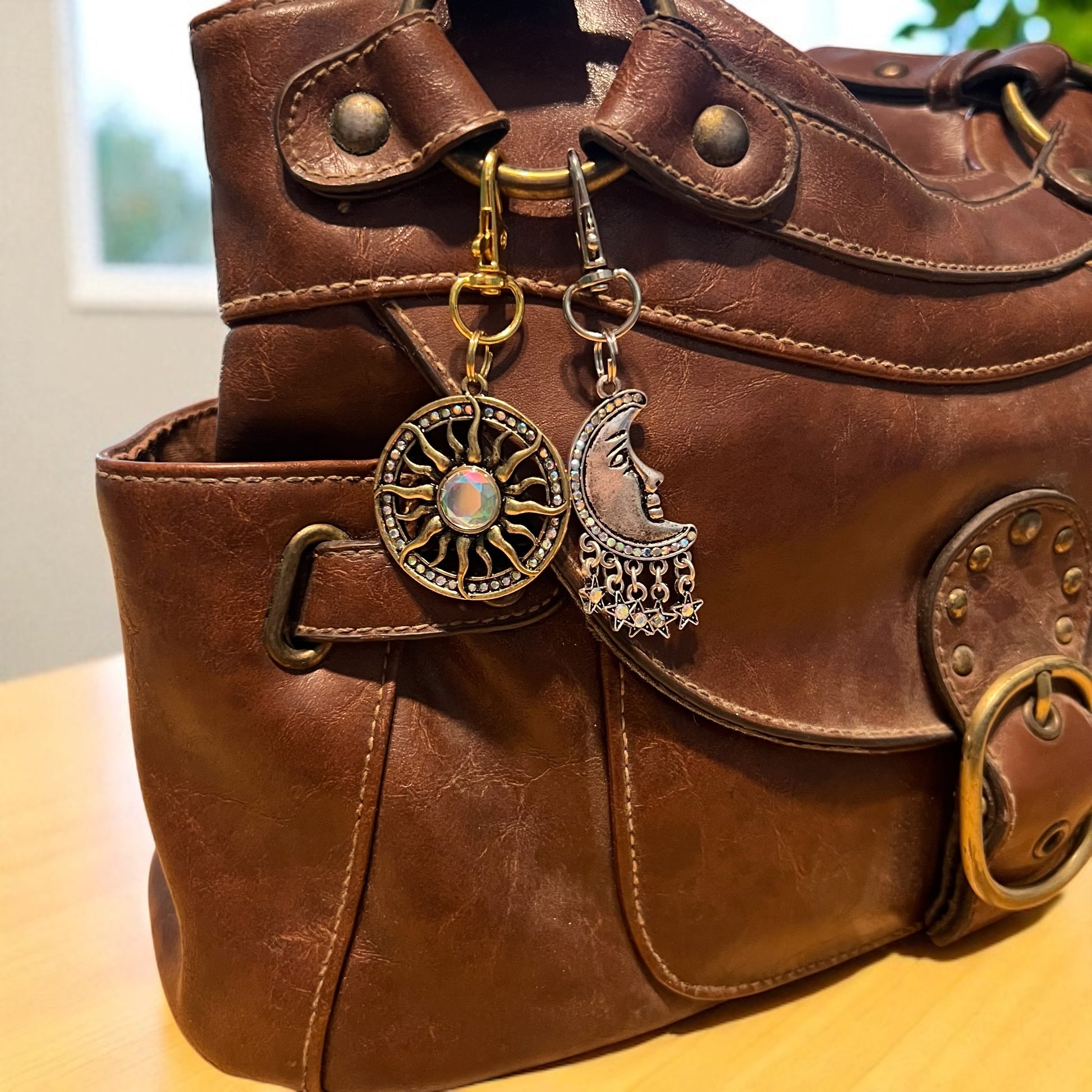 Brown leather handbag with decorative charms on a wooden surface