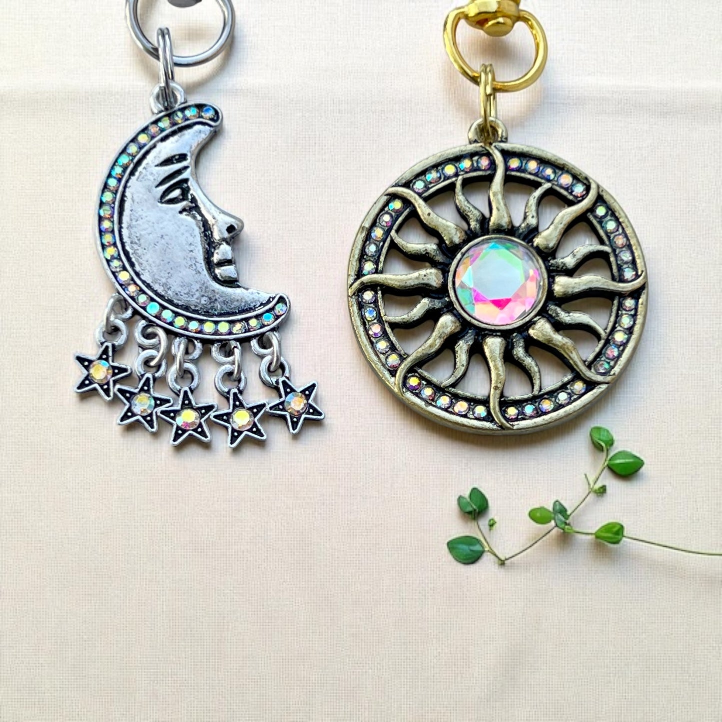 Two decorative keychains, one with a moon and stars design and the other with a sun design, on a light background.