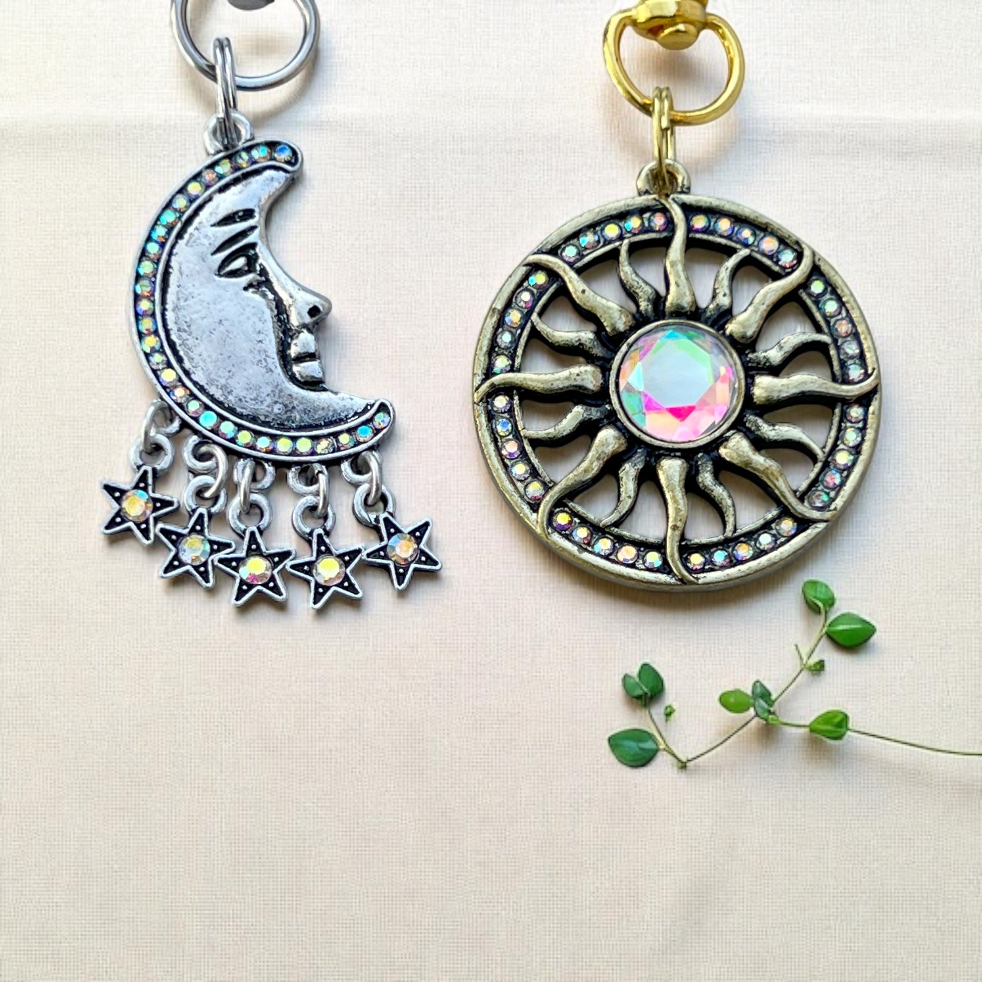 Two decorative keychains, one with a moon and stars design and the other with a sun design, on a light background.