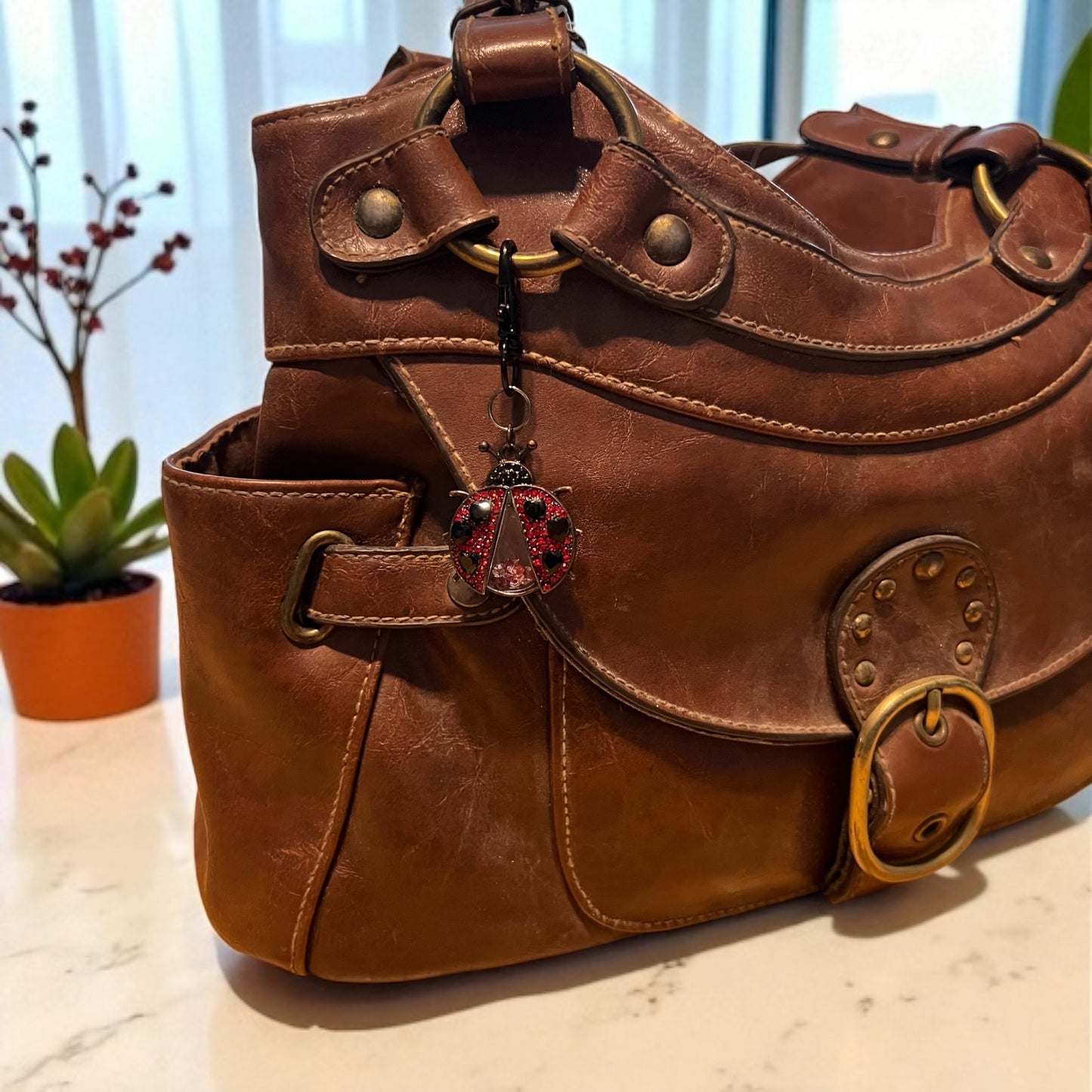 Brown leather handbag with decorative charm on a light surface