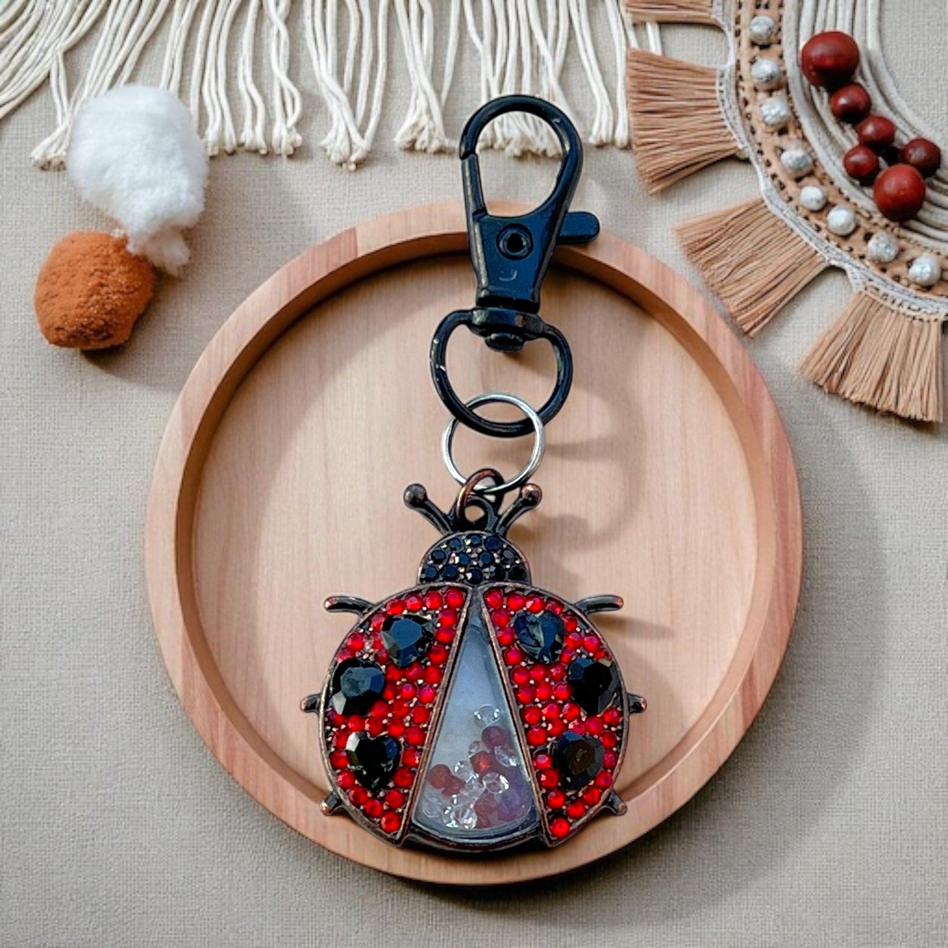 Decorative keychain shaped like a ladybug on a wooden plate with a neutral background