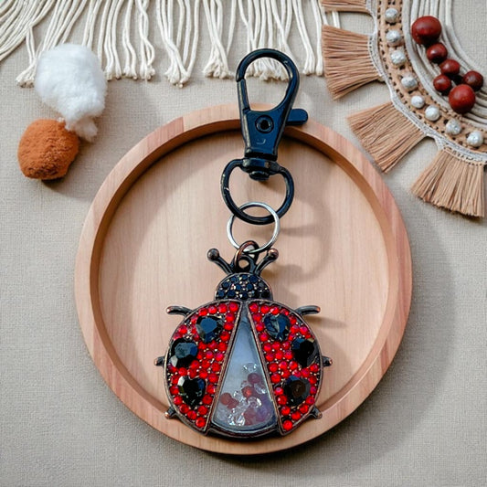 Decorative keychain shaped like a ladybug on a wooden plate with a neutral background