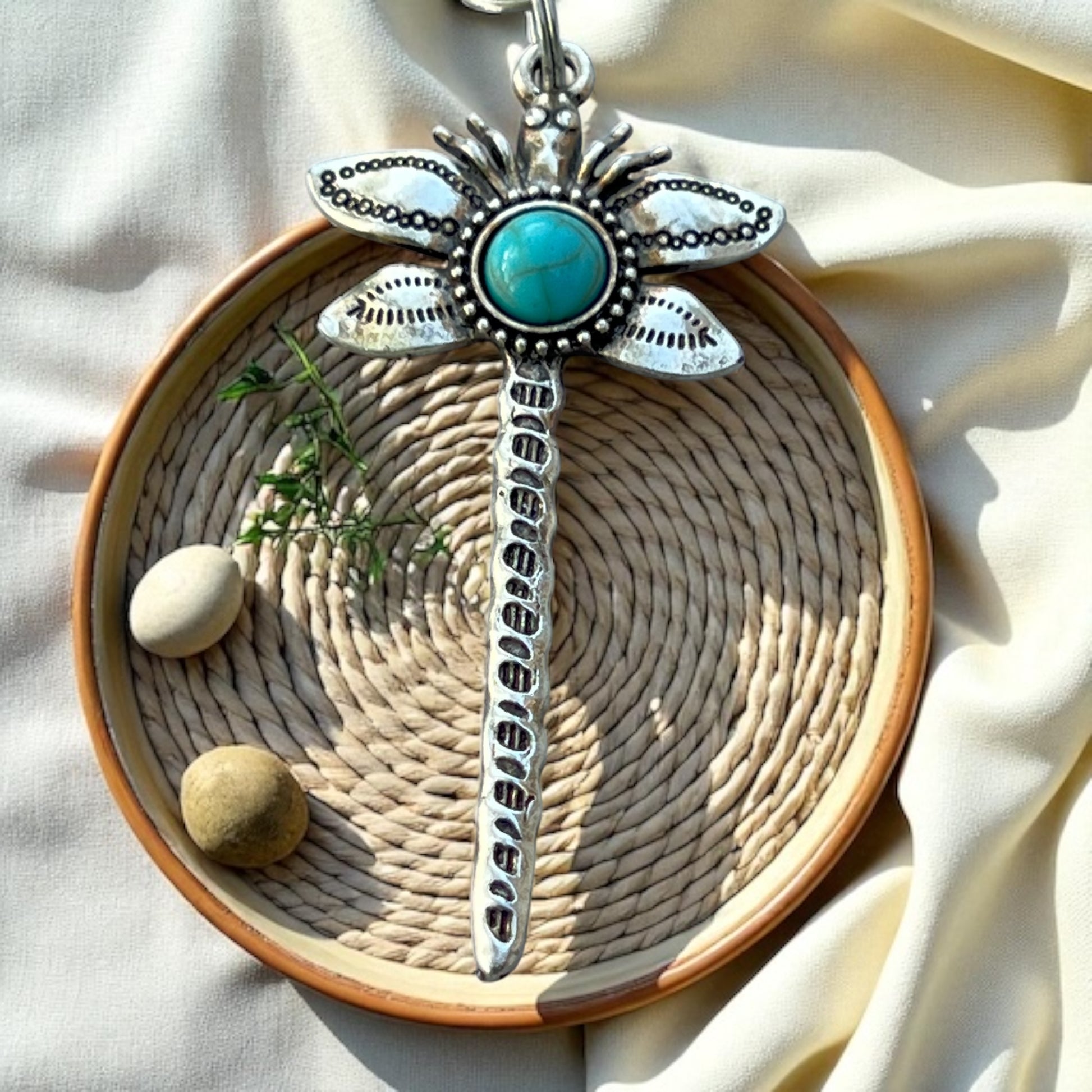 Decorative dragonfly purse charm with turquoise stone on a woven mat