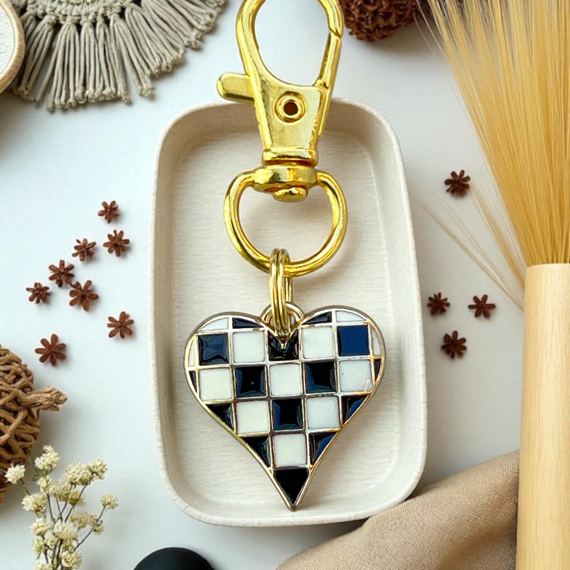 Heart-shaped keychain with gold clasp on a white dish surrounded by decorative items