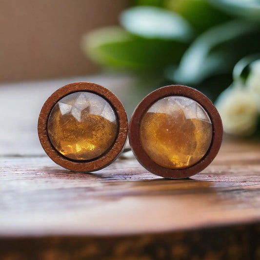 Round wooden earrings with embedded stones on a wooden surface.