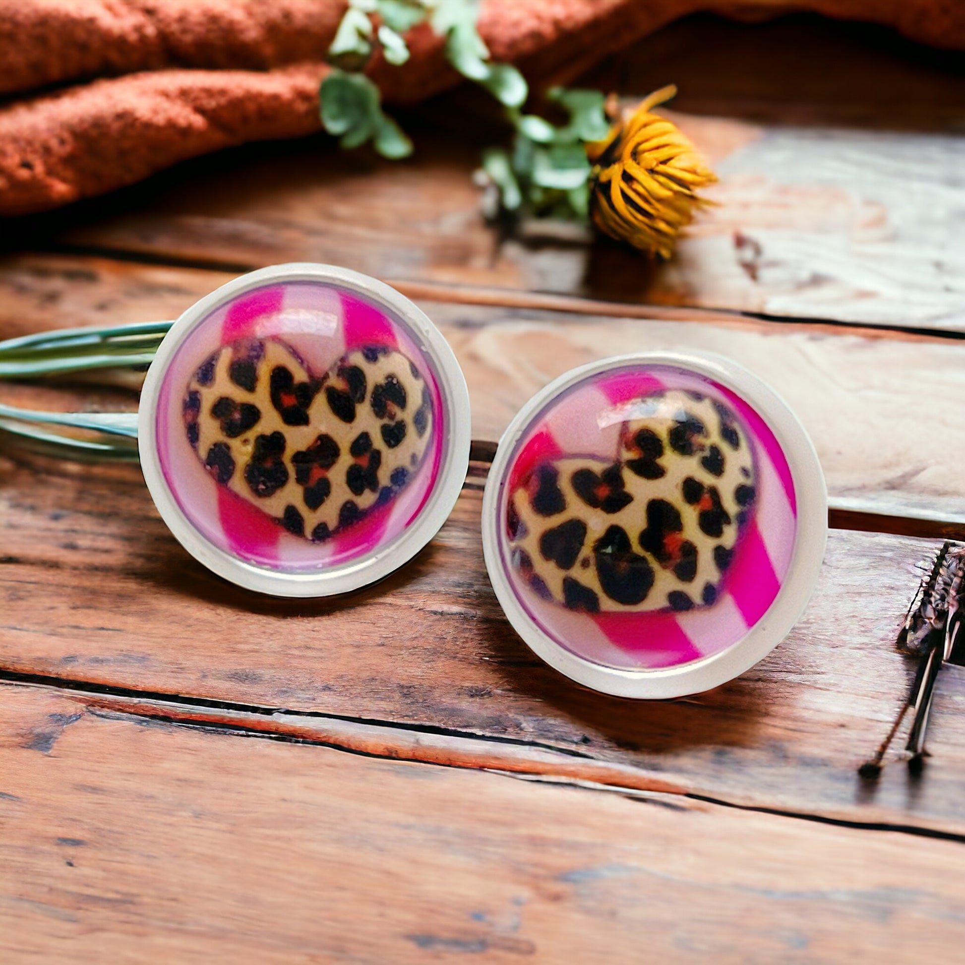 Cheetah print heart stud earrings shown in hand to show size and detail