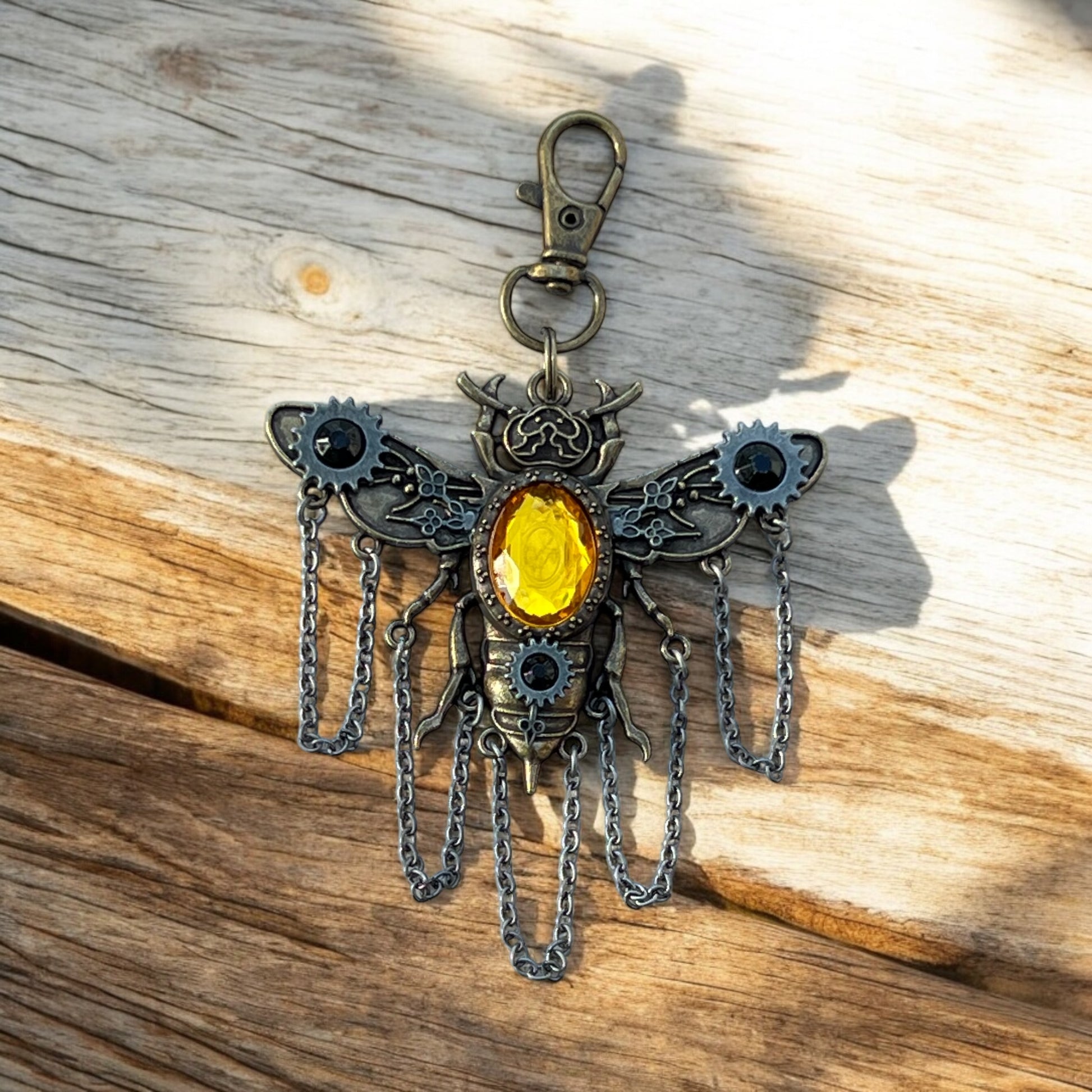 Steampunk bee charm photographed outdoors with fall leaves