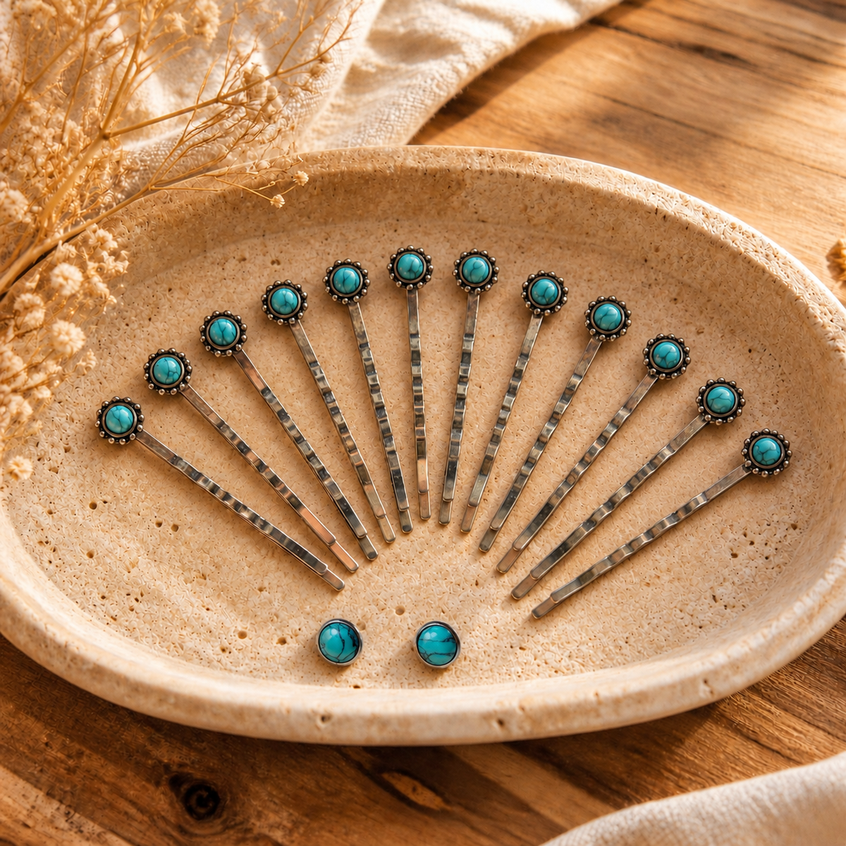 Styled illustration of F31-12E: twelve silver-tone faux-turquoise bobby pins and two matching round 10mm silver-tone stud earrings resting naturally inside a warm cream stone tray