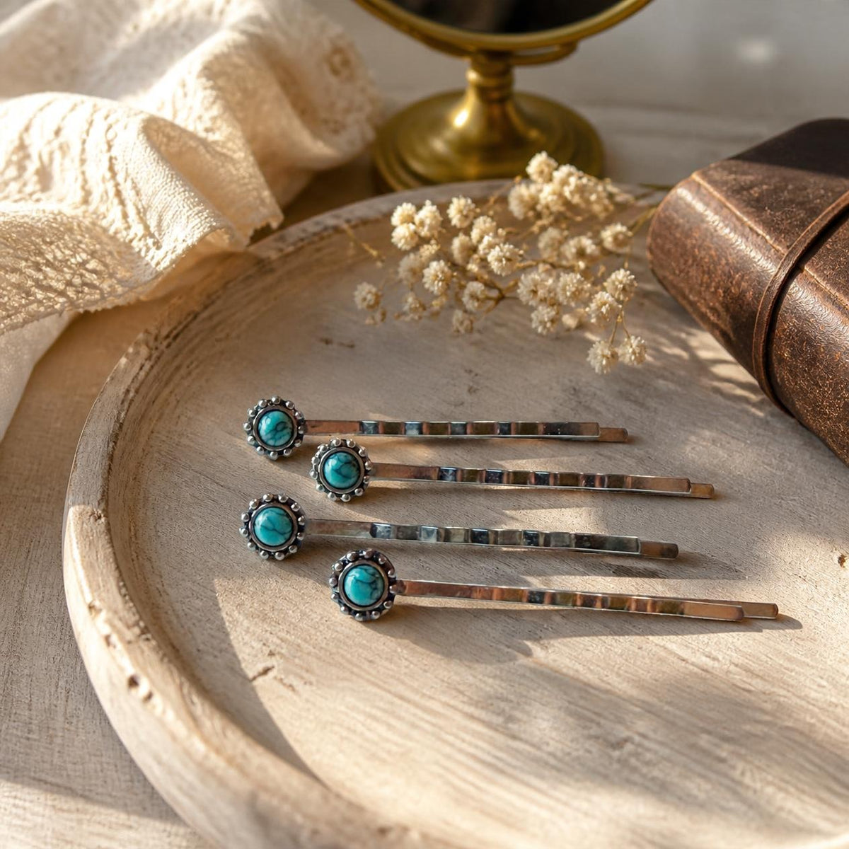 Four silver-tone turquoise western hair pins styled on an ivory-lined rustic wood vanity tray with cream flowers