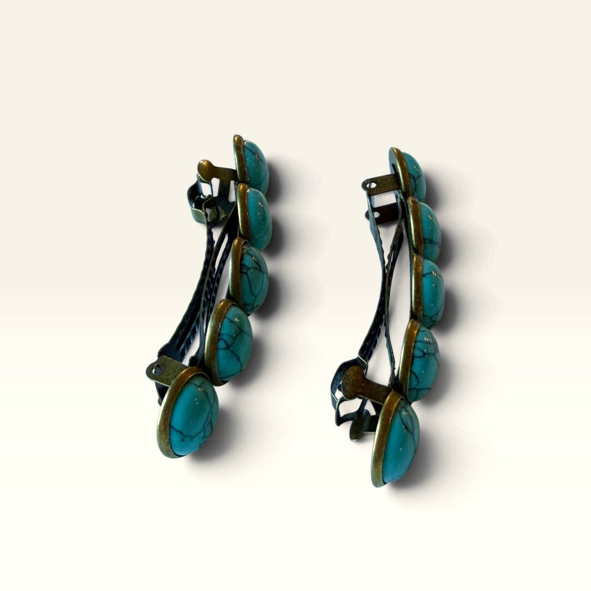 Side profile of two bronze-tone turquoise barrettes in the matching stud earring gift set