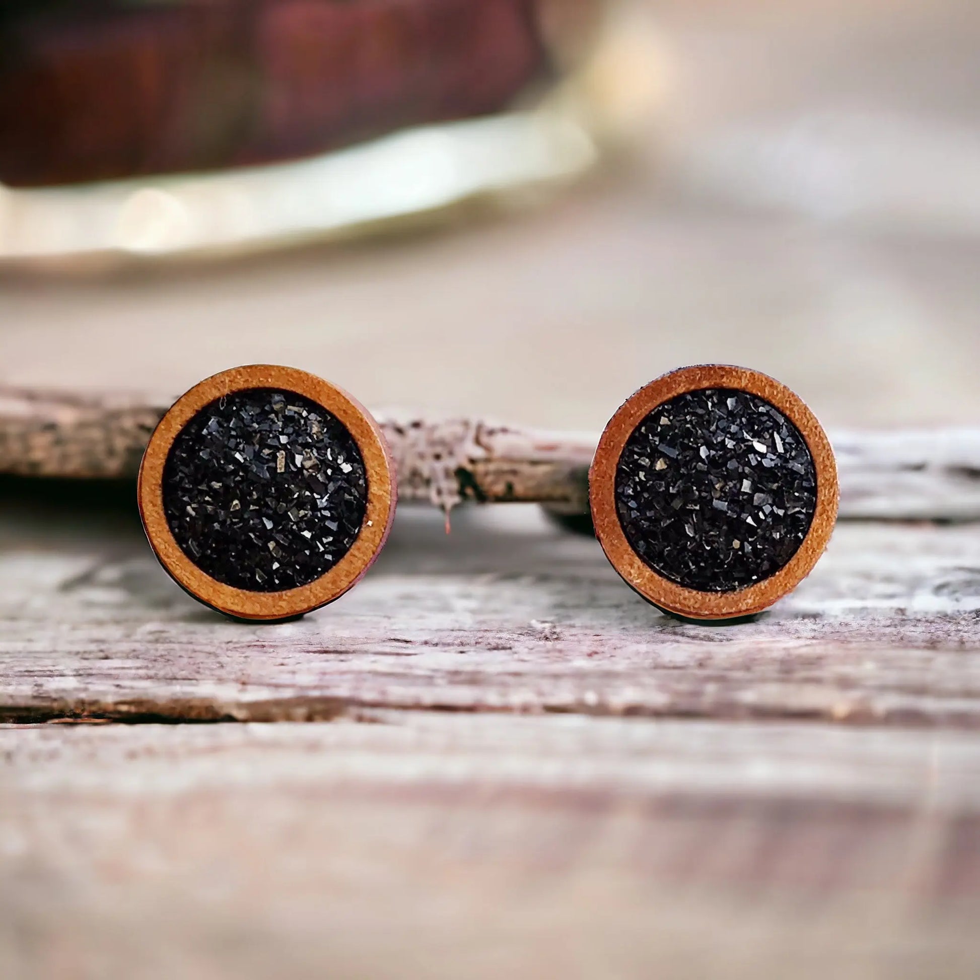 Round black druzy wood stud earrings displayed on a wood surface