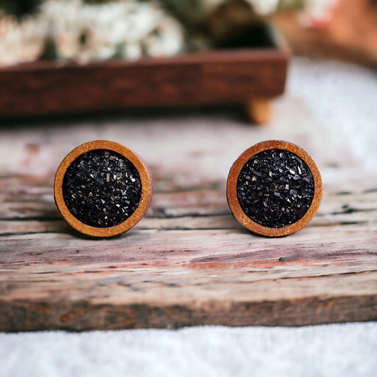 Round black druzy wood stud earrings displayed on a rustic wood surface