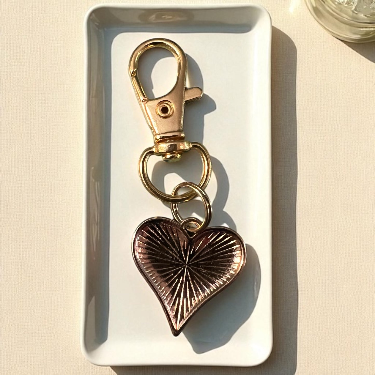 Gold and bronze heart-shaped keychain on a white tray