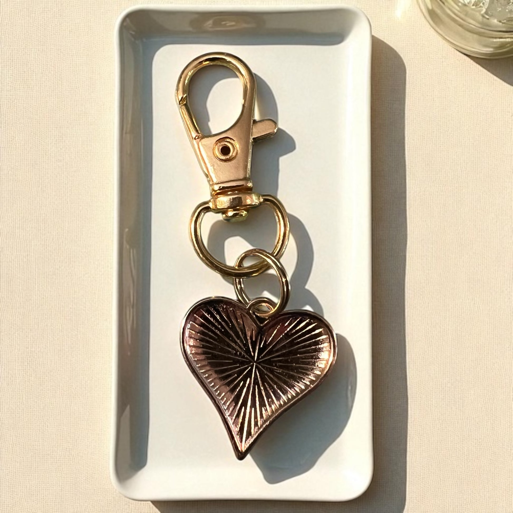 Gold and bronze heart-shaped keychain on a white tray