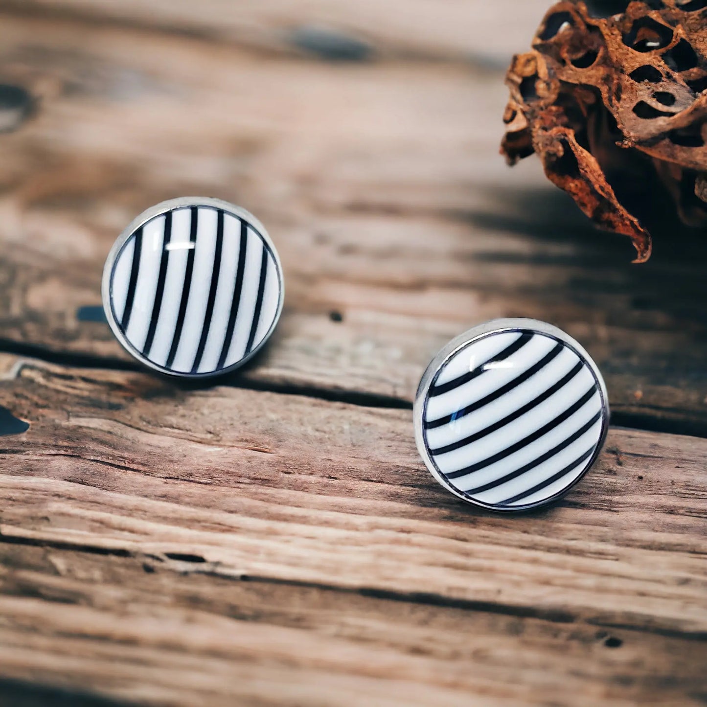 Pair of black and white striped earrings on a boho wooden surface