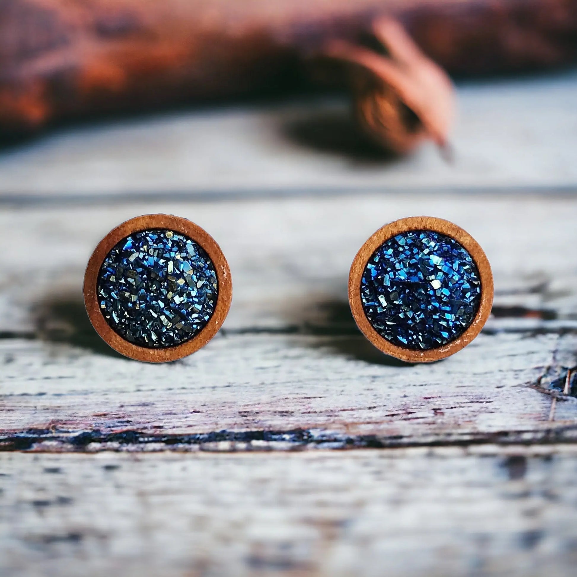 Round blue druzy wood stud earrings displayed on a white washed wood surface