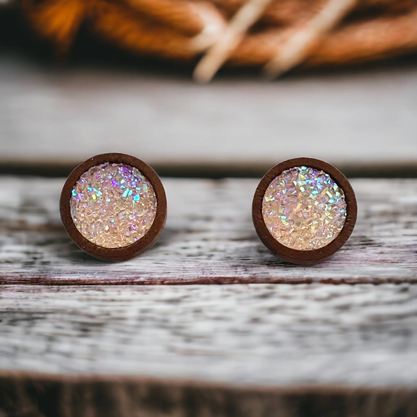 Round blush pink glitter druzy wood stud earrings displayed on a rustic boho wood surface