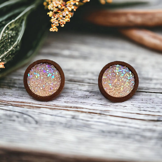 Round blush pink glitter druzy wood stud earrings displayed on a rustic wood surface