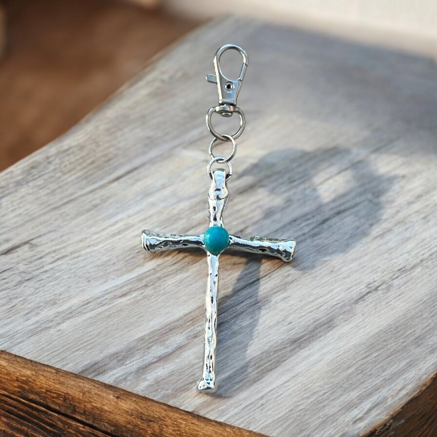 Side view of handmade turquoise cross handbag charm in antique silver