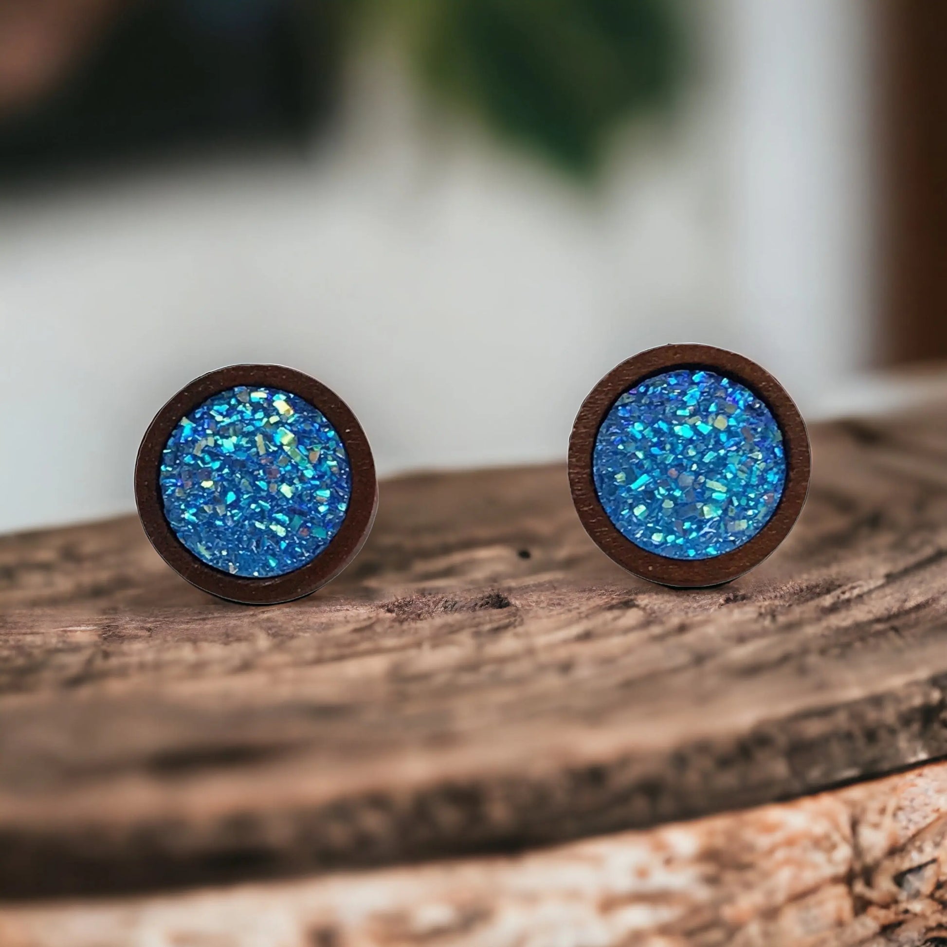 Round bright blue glitter druzy wood stud earrings displayed on a wood surface