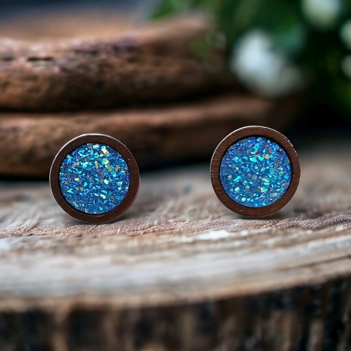 Round bright blue glitter druzy wood stud earrings displayed on a rustic boho wood surface