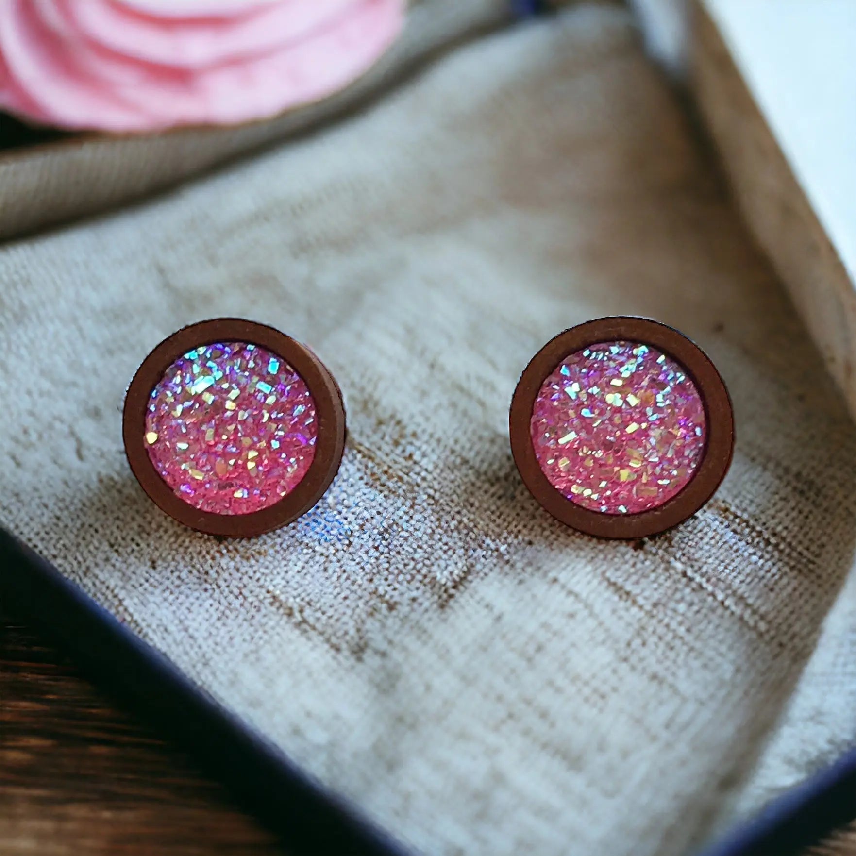 Round bright pink glitter druzy wood stud earrings displayed on fabric display 