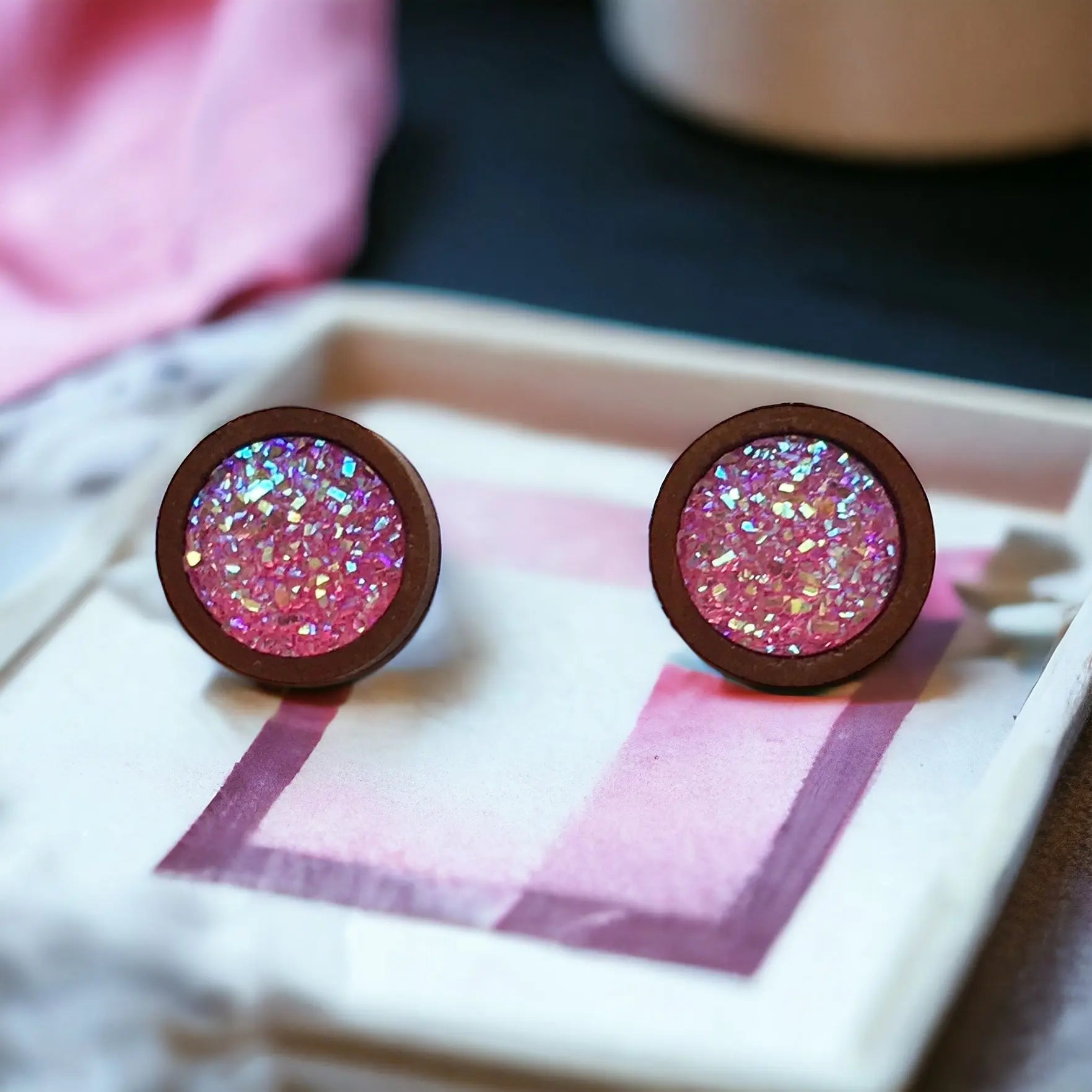 Round bright pink glitter druzy wood stud earrings displayed on a decorative white tray