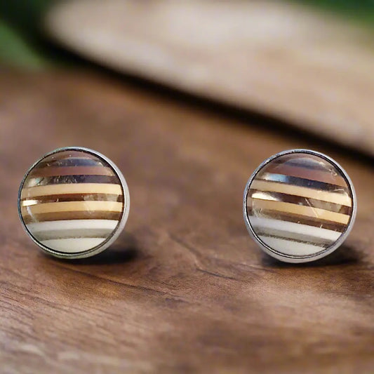 Round brown striped stud earrings in a silver-tone setting displayed on a dark wood surface