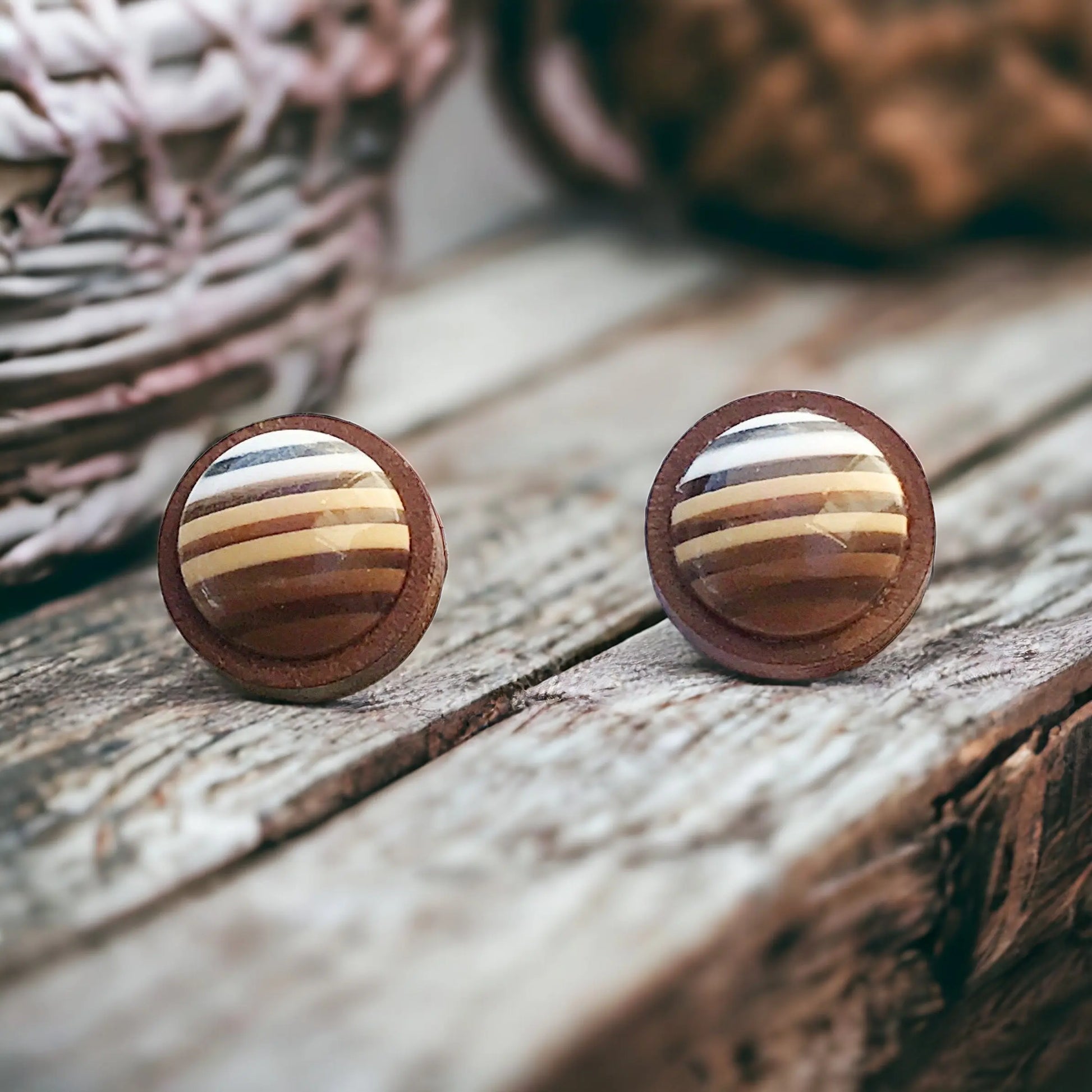 Round brown striped wood stud earrings displayed on a rustic boho wood surface