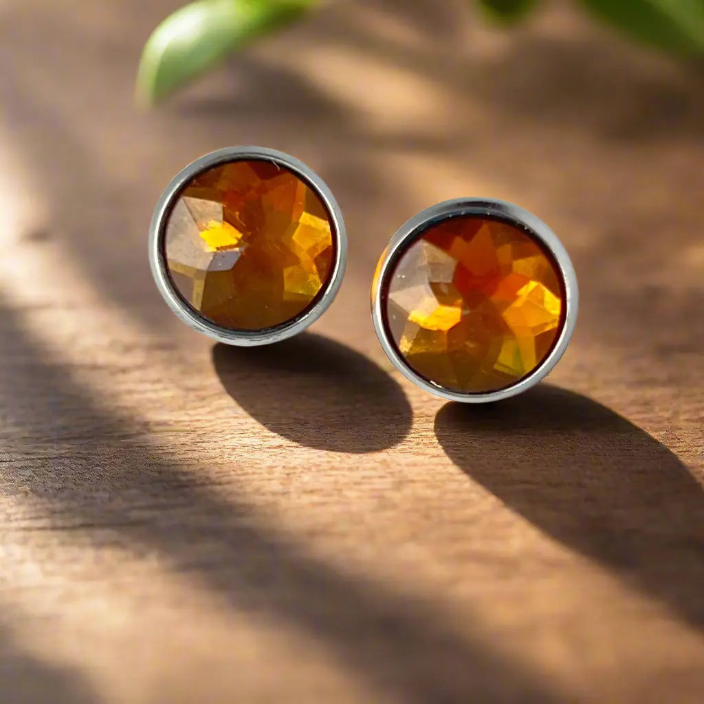 Pair of amber-colored stud earrings on a wooden surface with natural light.