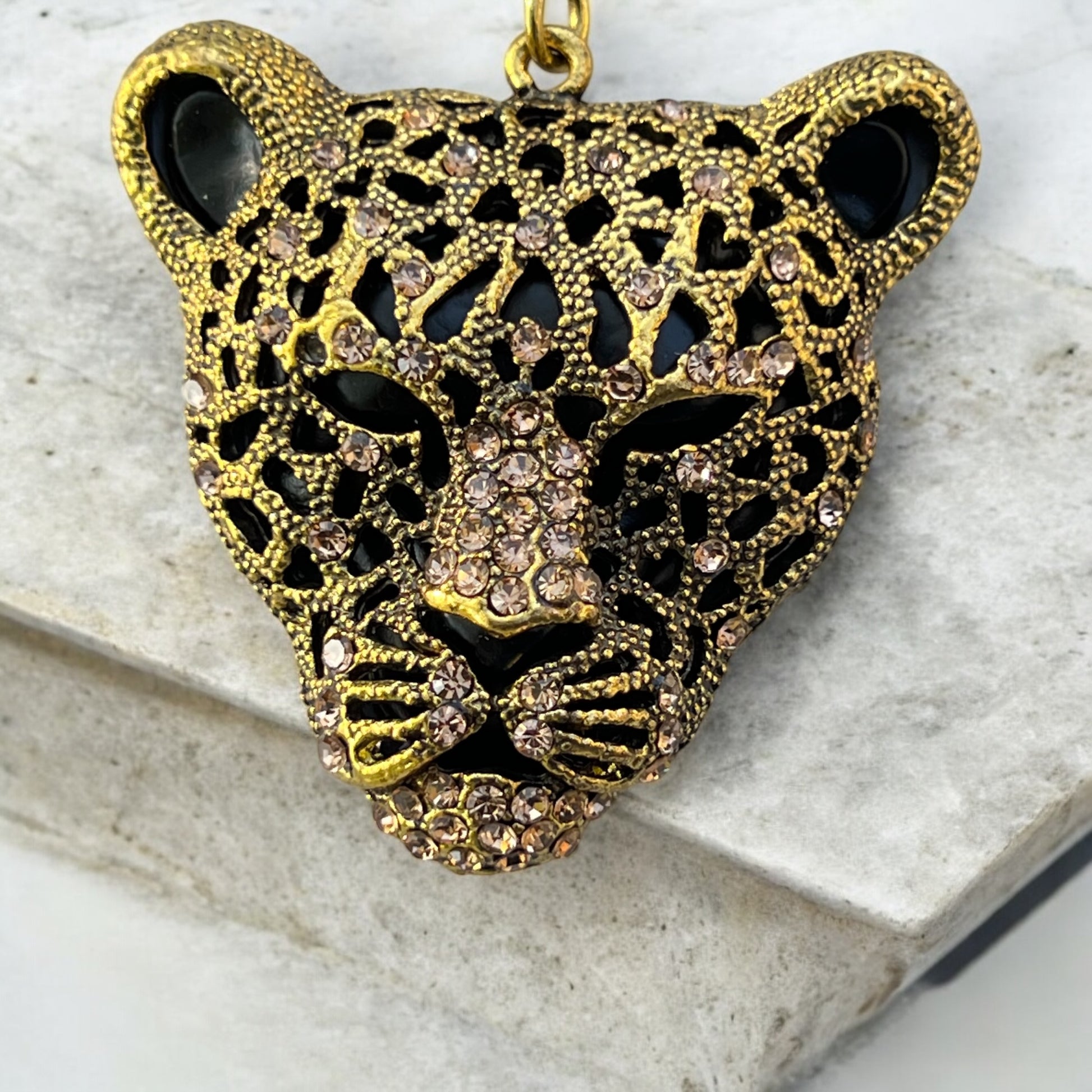 Close-up of black and amber rhinestone cheetah charm in antique brass