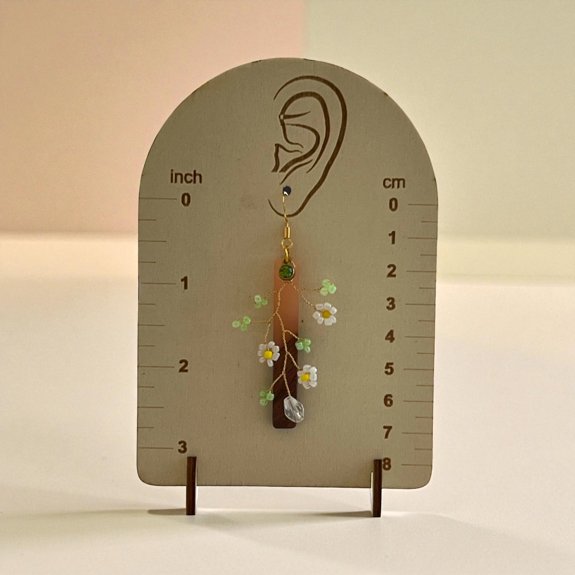 Earring displayed on a measurement card with floral design