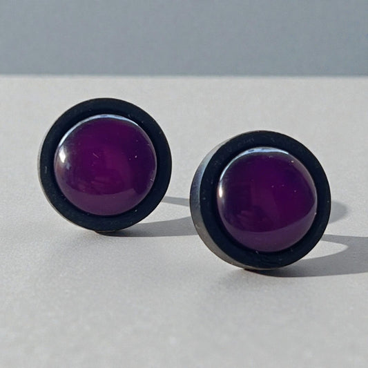 Pair of round purple earrings with black wood rims on a light gray background