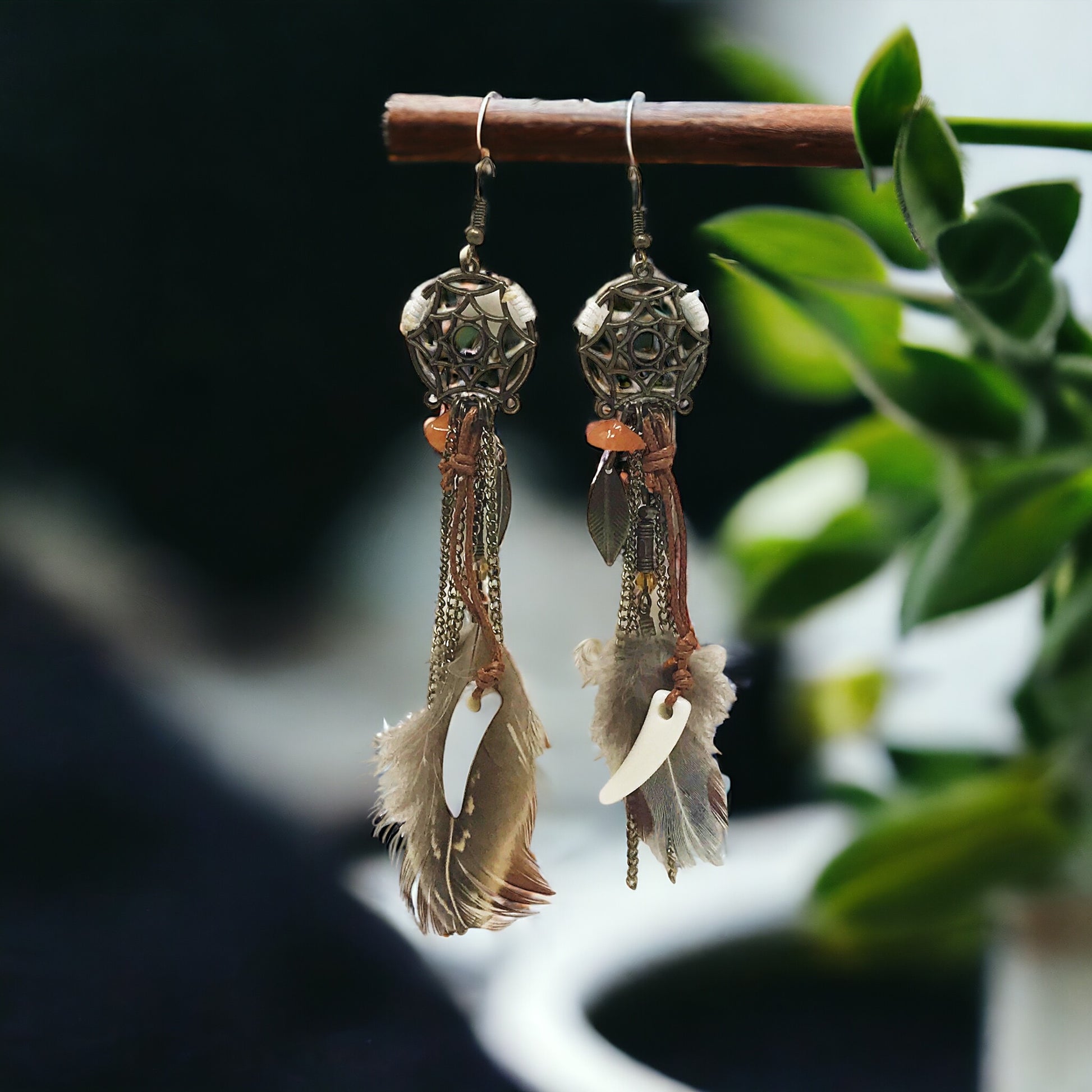 Earrings hanging from a display branch with a warm-toned natural backdrop